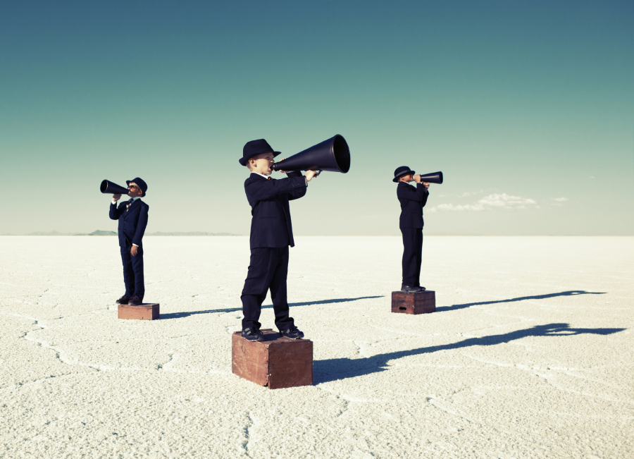 Three boys with megaphones in the desert.