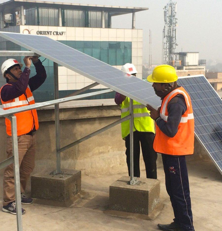 Local engineers install a rooftop solar system in Gurgaon, India.