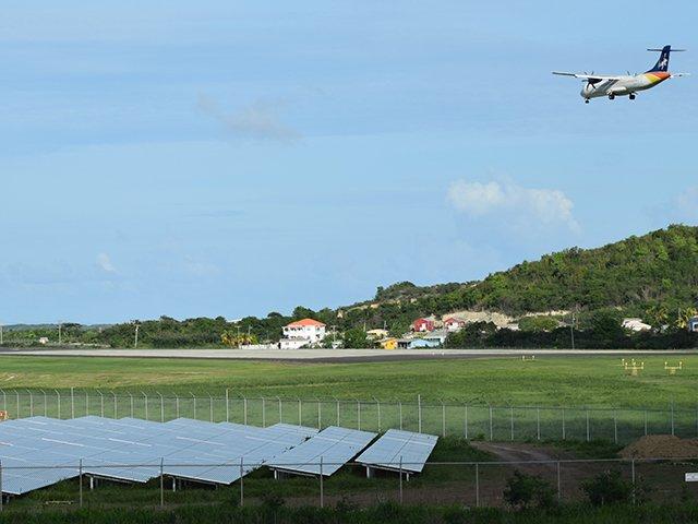 An airplane landing at the V.C. Bird International Airport Antigua, next to the solar power plant.