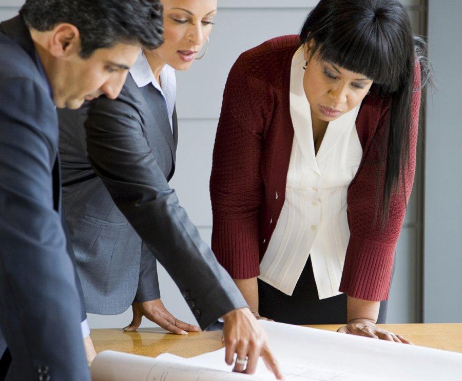 Three business persons discussing a draft.