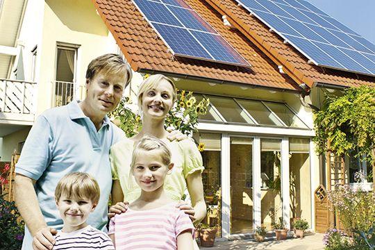 A family in front of their house with solar rooftop installation.