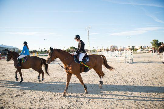 Two riders and horses of The Petra Energy S.R.O Equestrian Team during a competition.