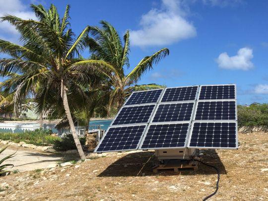 The off-grid solar solution sun2go xl installed in Antigua and Barbuda next to palm trees.