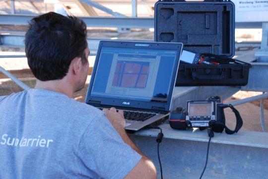 Engineer with laptop and camera at a solar installation.